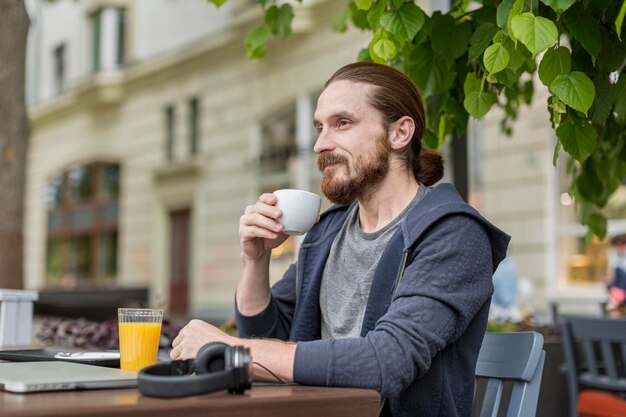 Side view of man enjoying coffee at a city terrace