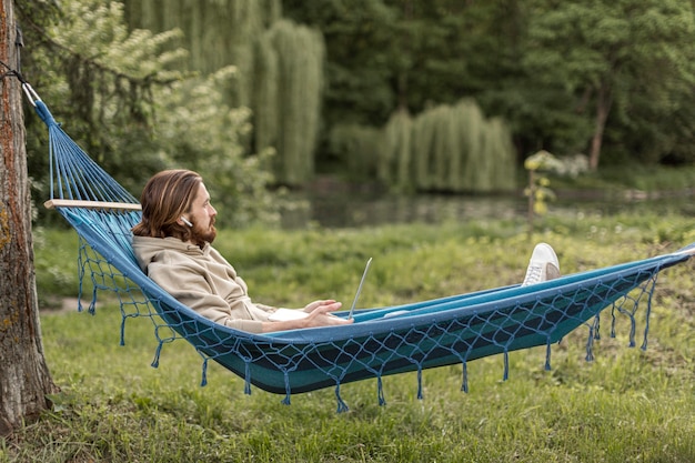 Side view of man enjoying nature in hammock