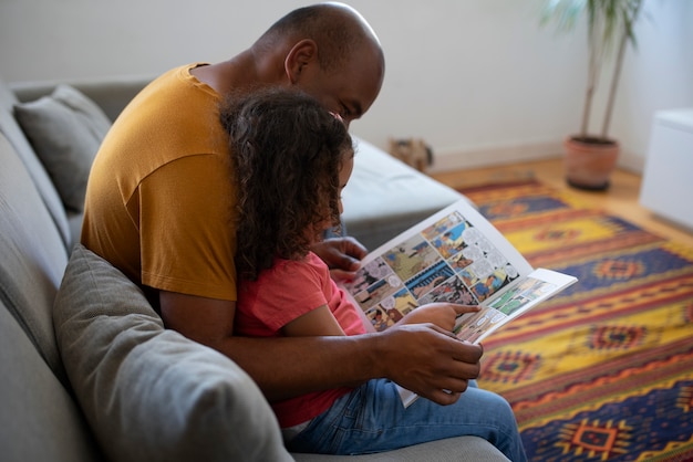 Side view man and girl reading comics at home