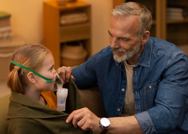 Free photo side view man and girl with nebulizer