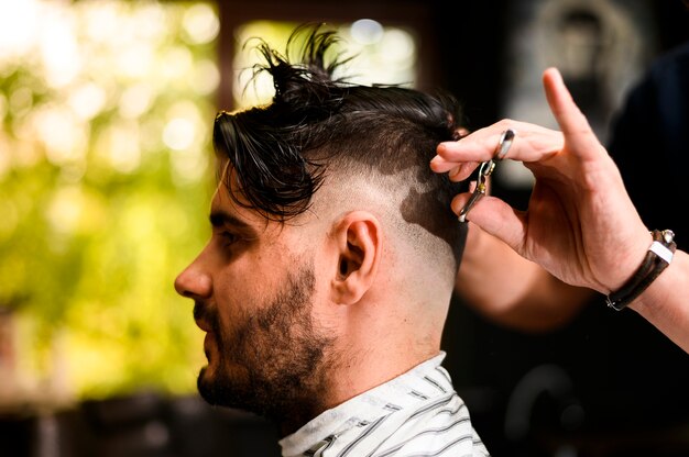 Side view of man having his hair cut