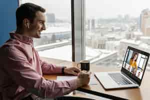 Free photo side view of man having an online video call with coworkers