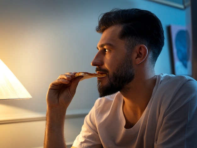 Foto gratuita uomo di vista laterale che mangia spuntini di notte