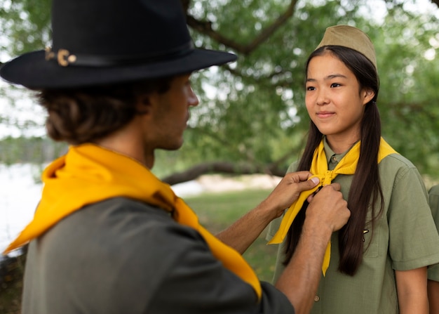 Foto gratuita uomo di vista laterale che aiuta la ragazza scout