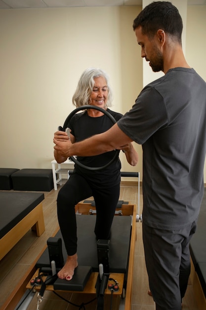 Free photo side view man helping woman in pilates class