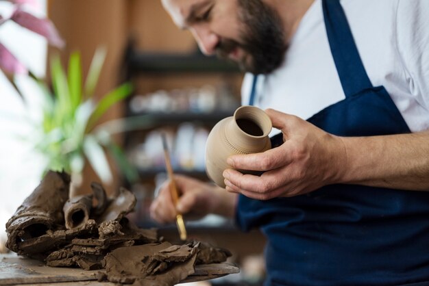 Side view man holding brush and vase