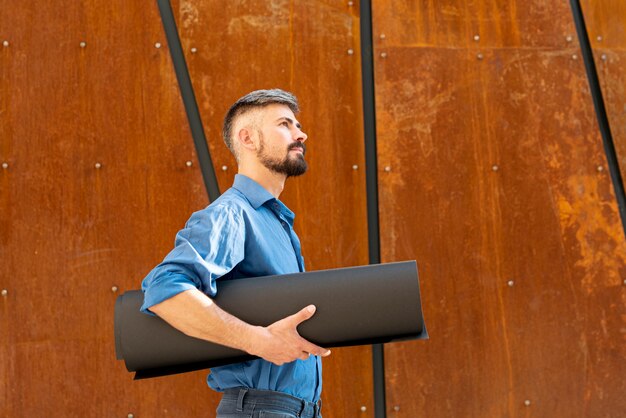 Side view of man holding building schematics