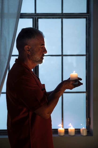 Вид сбоку мужчина держит зажженную свечу