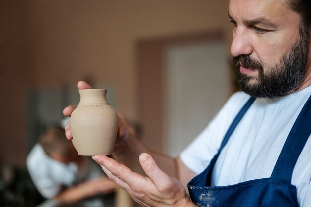 Side view man holding little vase