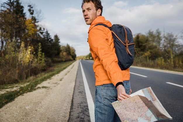 地図を保持し、道路に沿って歩く男の側面図