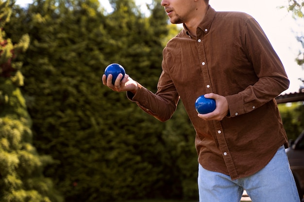 Free photo side view man holding metallic balls