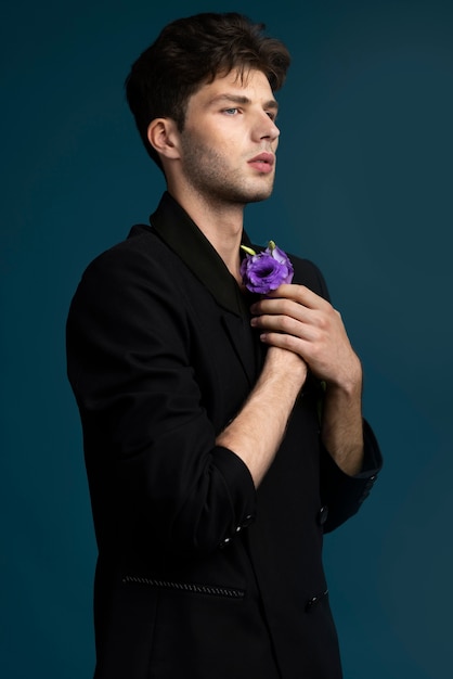 Вид сбоку мужчина держит фиолетовый цветок