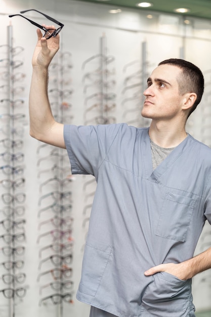 Free photo side view of man holding up pair of glasses