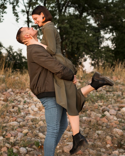 Free photo side view man holding up woman