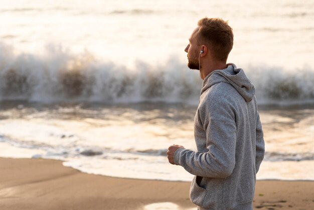 Side view man jogging on sand