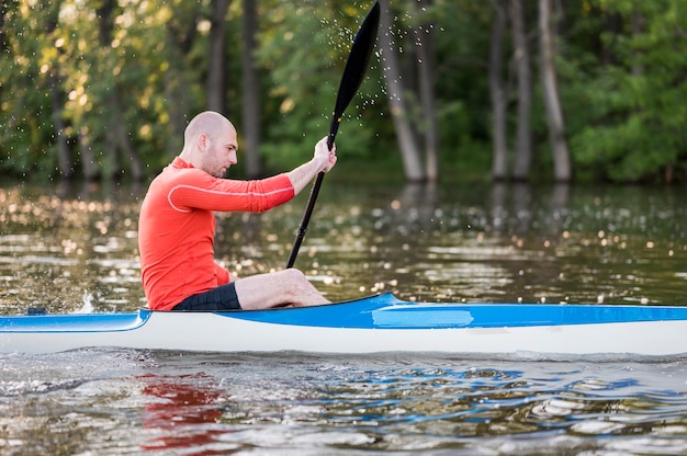 Side view man in kayak with oar