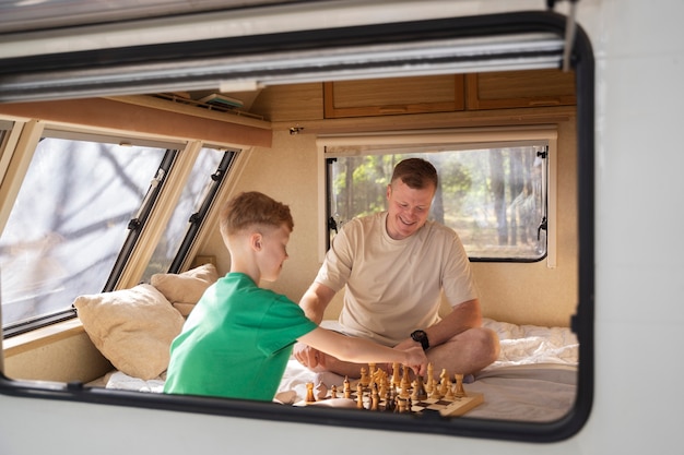 Free photo side view man and kid playing chess