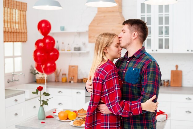 Side view man kissing woman on the forehead