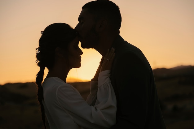 Side view man kissing woman on forehead