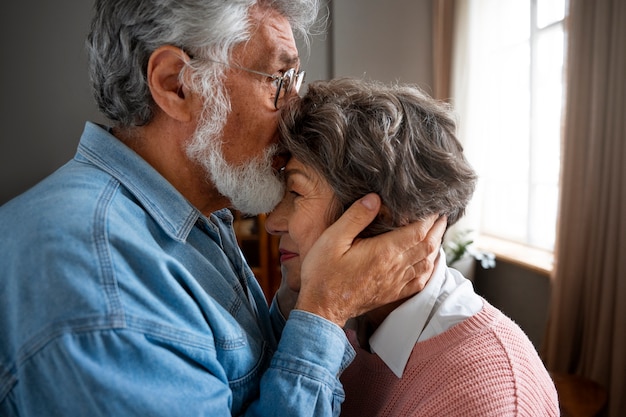 Free photo side view man kissing woman on forehead