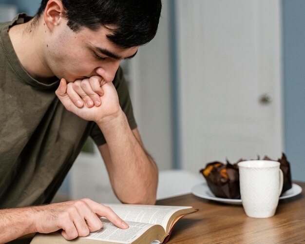 Side view of man in the kitchen reading from the bible