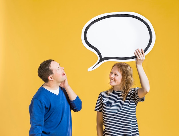 Side view of man looking at chat bubble woman is holding