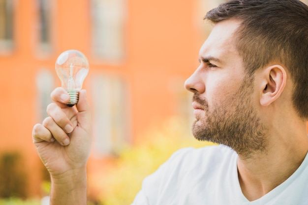 Free photo side view of man looking at light bulb