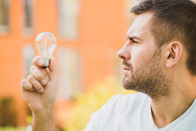 Side view of man looking at light bulb