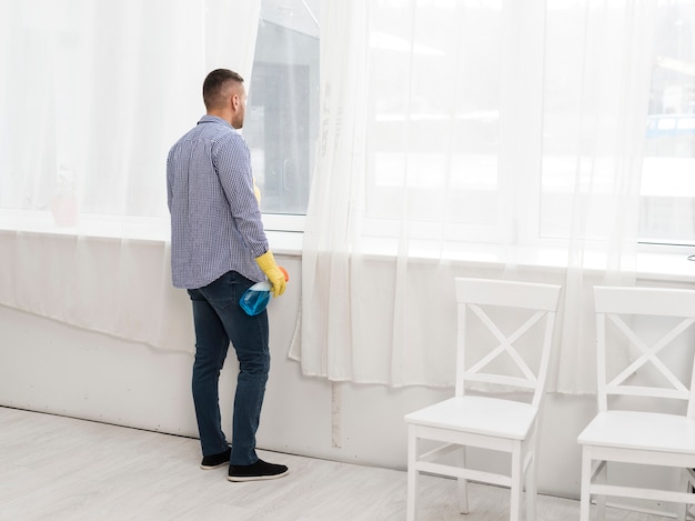 Side view of man looking through window while cleaning