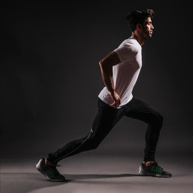 Side view man lunging on dark background