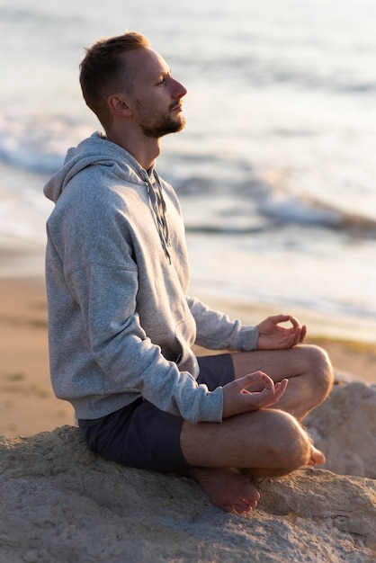 Side view man meditating on the beach