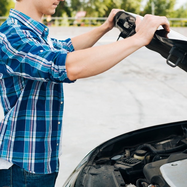 Side view of man opening car hood