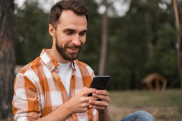 スマートフォンを屋外で見ている男の側面図