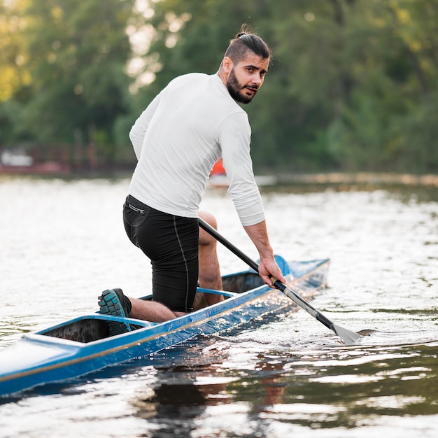 Foto gratuita vista laterale uomo pagaiando in canoa