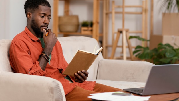 Free photo side view of man planning on redecorating home using laptop and book