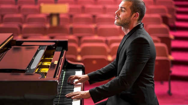 Free photo side view man playing classical piano recital