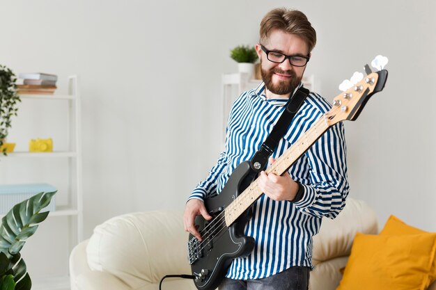 Side view of man playing electric guitar at home