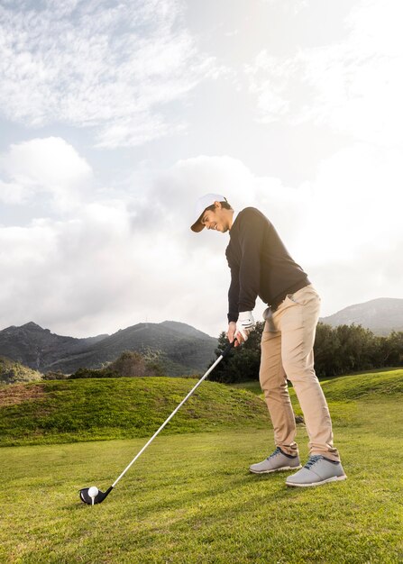 Side view of man playing golf on the field with club and copy space