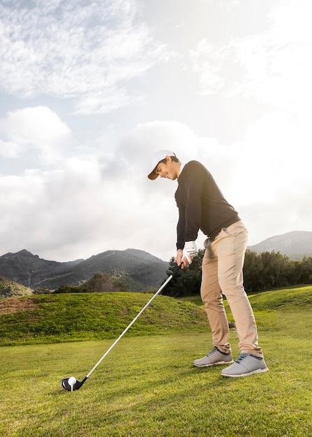 Side view of man playing golf on the field with club and copy space