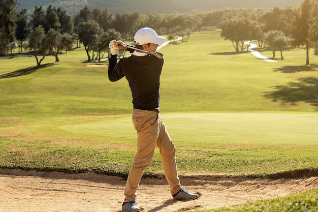 Вид сбоку человека, играющего в гольф с клюшкой