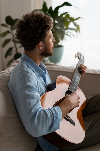 Free photo side view man playing the guitar