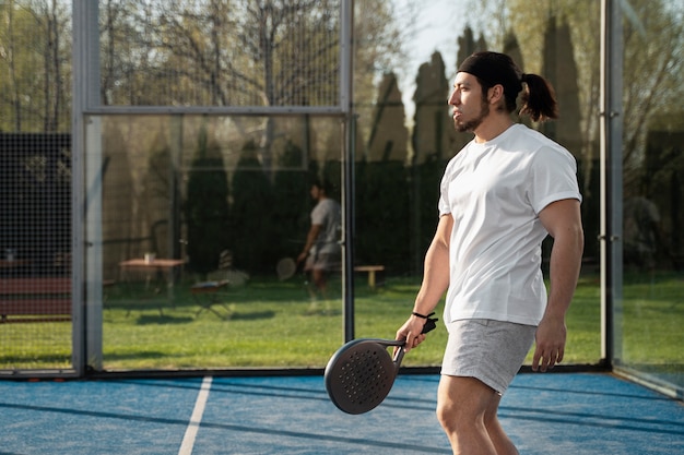 Free photo side view man playing paddle tennis