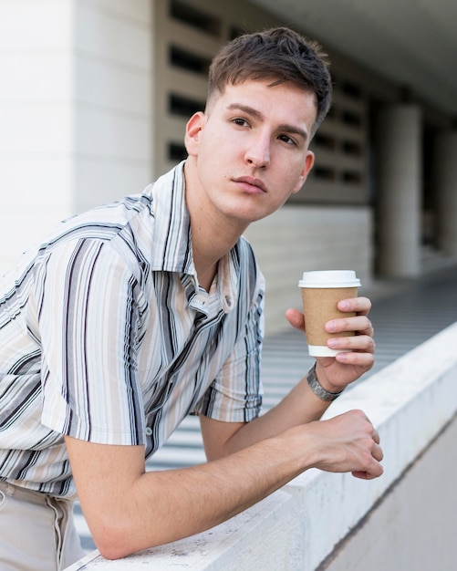 Side view of man posing outdoors with coffee