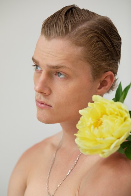 Side view man posing with flower in studio