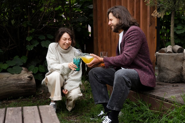 Free photo side view man pouring drink for smiley woman