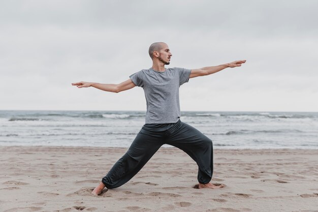 Вид сбоку человека, практикующего позы йоги на открытом воздухе