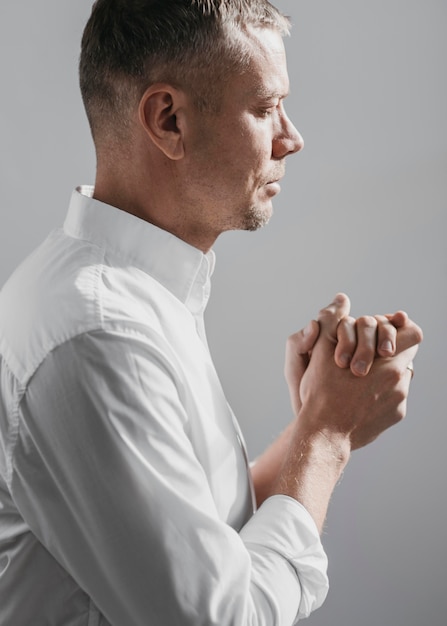 Free photo side view man praying at divinity at home