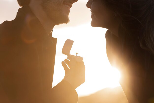 Free photo side view man proposing to woman with ring