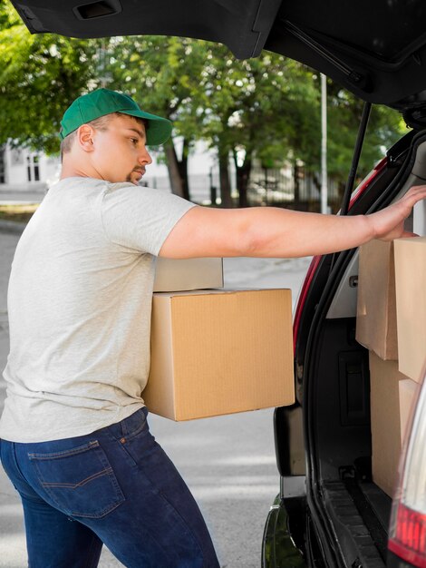 Side view man putting boxes in trunk