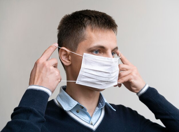 Side view of man putting on medical mask